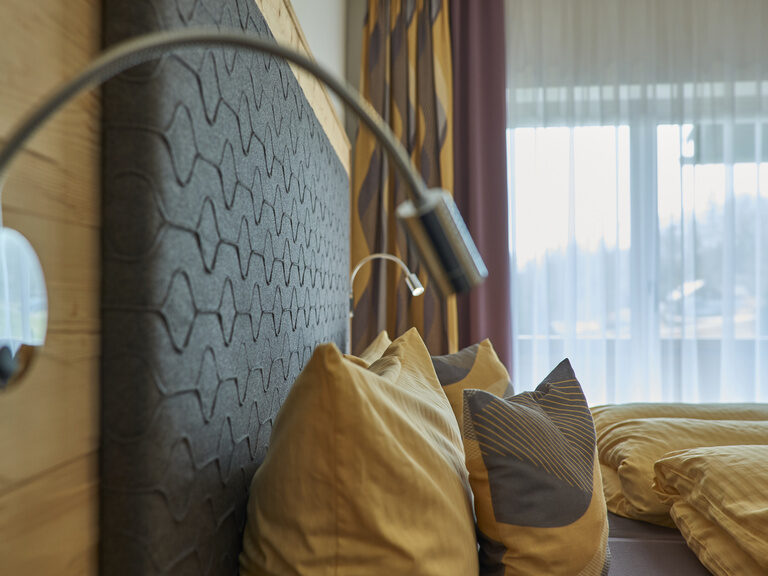 Ein gemütliches Bett in der Pension Kilger, mit herrlichem Blick aus dem weitläufigen Balkonfenster.