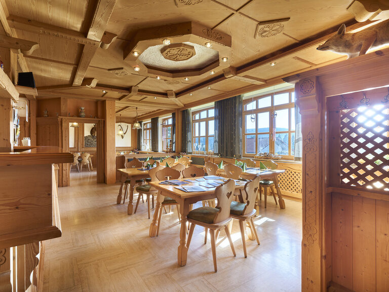 Die traditionell gestaltete Gaststube der Pension Kilger mit großen Fenstern, die eine hervorragende Aussicht bieten, und komfortabler hölzerner Einrichtung.