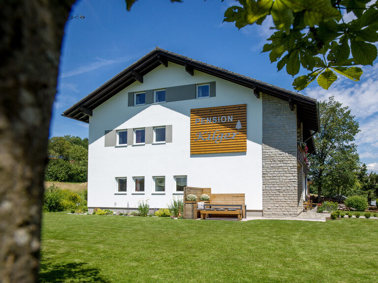 Außenansicht des modernen Hauses der Pension Kilger bei Sonnenschein im Garten.
