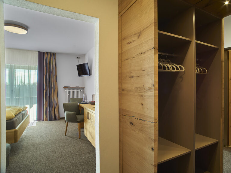 Der Eingangsbereich eines Zimmers der Pension Kilger der zum gemütlichen Schlafzimmer mit guter Aussicht führt und mit einem modernen Holzkleiderschrank ausgestattet ist.